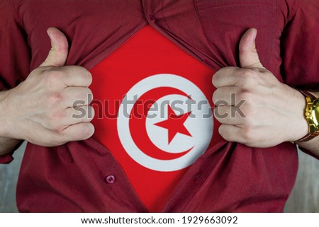 Young sport fan opening his shirt and showing the flag Tunisia