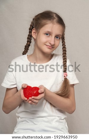 Girl in a white t-shirt holding a red heart
