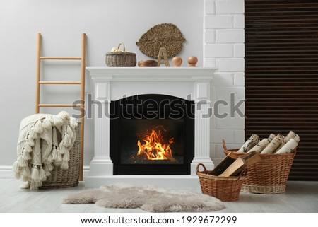 Wicker baskets with firewood and white fireplace in cozy living room Royalty-Free Stock Photo #1929672299