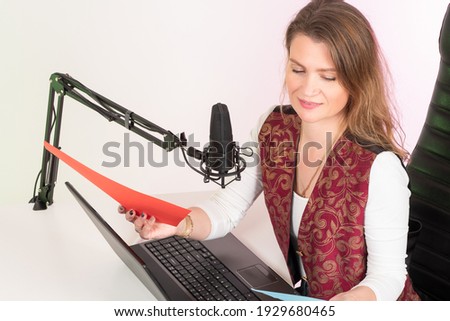 A girl records a podcast. A long-haired girl in a recording Studio. A woman sits in front of a microphone. A woman leads a radio show.