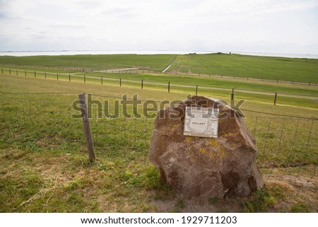 wetland behind the sea wall or dike at the mercy of ebb and flow, stone statue with map and name tag, plaque of the Dollard nature reserve