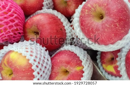 A bunch of big red apples wrapped in foam nets