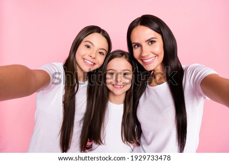 Photo portrait of smiling happy family mother and daughters talking selfie together isolated pastel pink color background