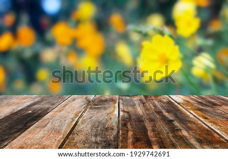 Empty dark wooden table in starburst flower blooming on blurred background.