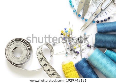 Blue and yellow sewing accessories template with scissors, tape measure, spool of thread and needle isolated un cut-out on white background. Royalty-Free Stock Photo #1929745181