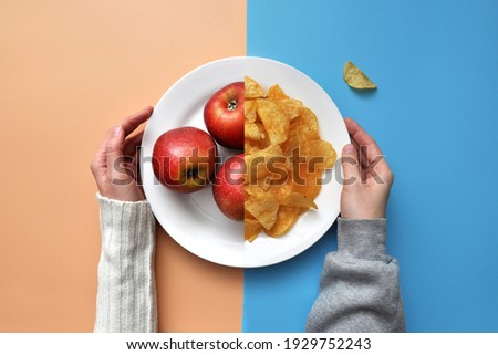 a plate of chips and red apples. A person chooses between healthy and unhealthy food Royalty-Free Stock Photo #1929752243