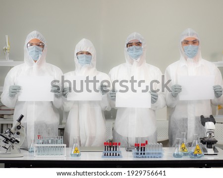 Asian doctor team holding billboard. Scientists in protective equipment hold blank paper in hands. Copy space 