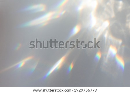 Blurred rainbow light refraction texture overlay effect for photo and mockups. Organic drop diagonal holographic flare on a white wall. Shadows for natural light effects Royalty-Free Stock Photo #1929756779
