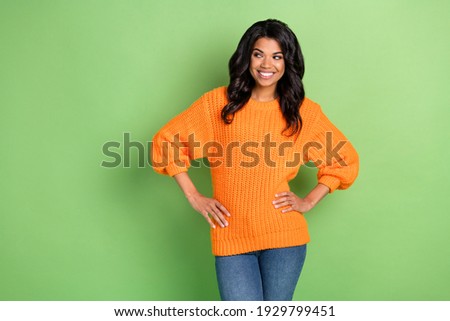 Portrait of attractive cheerful girl hands on hips looking aside thinking guessing copy space isolated over green pastel color background