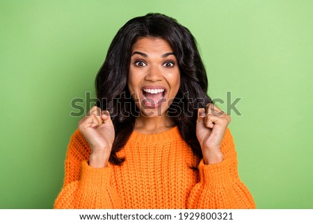 Photo of funny lucky dark skin lady dressed knitted pullover rising fists isolated green color background