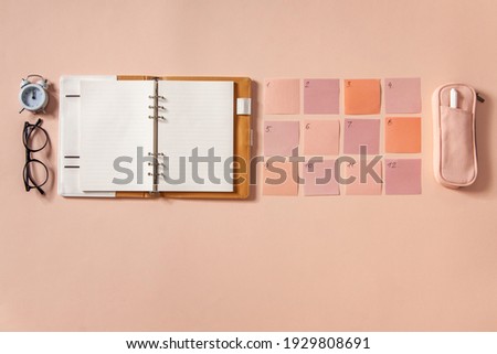 Flat lay of notepad with words Goals 2021, colorful sticky notes, o'clock, pen and pen case on coral colored background. Concept of creating and setting goals for New year.