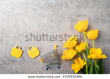 Concept of Mother's day holiday gift shopping greeting design with yellow tulip flower bouquet on gray background