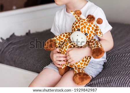 Child holding a giraffe plush toy on a gray background