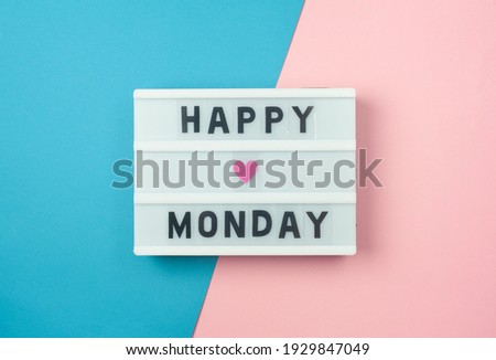 Happy Monday - text on display lightbox on blue and pink background.