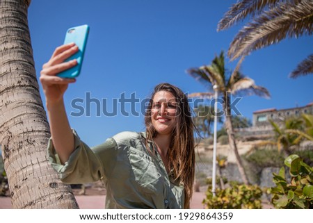 A beautiful tourist takes a selfie during her summer vacation in a tropical place.