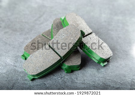 A set of four new car brake pads on a gray background.