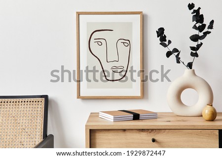 Stylish interior of living room with mock up poster frame, wooden commode, book, eucalyptus leaf in ceramic vase and elegant personal accessories. Minimalist concept of home decor. Template. Royalty-Free Stock Photo #1929872447