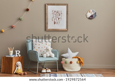 Cozy interior of child room with mint armchair, brown mock up poster frame, toys, teddy bear, plush animal, decoration and hanging cotton colorful balls. Beige wall. Warm kid space.  Template. 