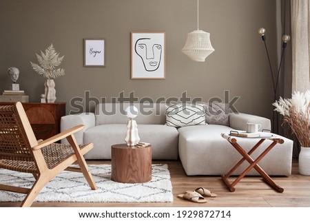 Stylish interior with design neutral modular sofa, mock up poster frames, rattan armchair, coffee tables, dried flowers in vase, decoration and elegant personal accessories in modern home decor.