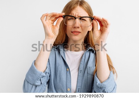Poor eyesight. Young woman with glasses squinting, trying to take a closer look, woman with poor eyesight on white background