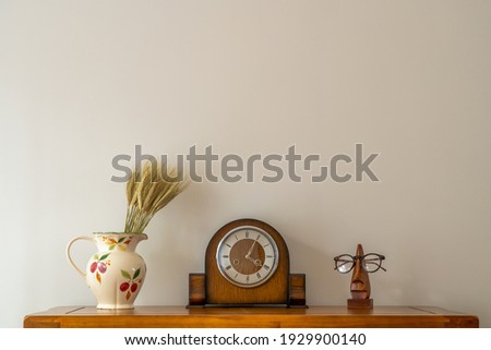 still life of antique clock with floral jug and optical prescription glasses on stand