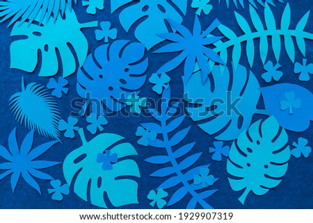 Creative background of tropical leaves on a green backdrop. View from above. Nature concept. Abstract background from paper tropical leaves.