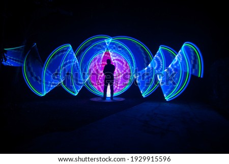 one person standing against beautiful blue and purple circle light painting as the backdrop