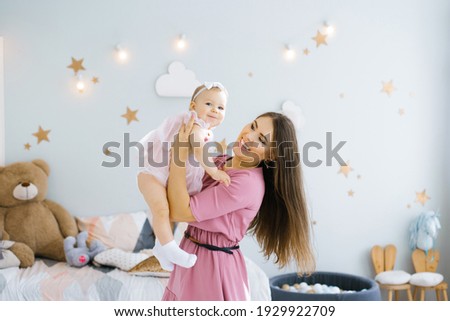 The concept of motherhood, infancy and people-the mother throws the child up, laughing and playing with it in the nursery