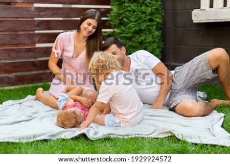 Happy family with two children on the green grass in the yard of their house.