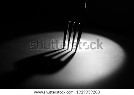 Fork from the side in the spotlights, abstact and in black and white