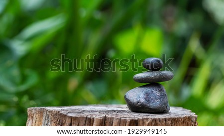 Three black stones stacked on a wooden base, zen