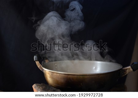 White smoke from cooking pot on stove in countryside kitchen and blurred black background. soft picture