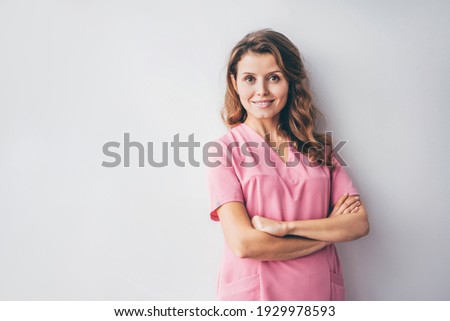 Portrait of charming beautician in pink lab coat looking at camera with smile.  Royalty-Free Stock Photo #1929978593