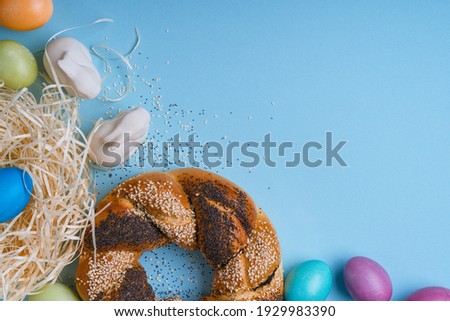 Eco-friendly Easter decor with natural, reusable, zero-waste materials, handmade dyed eggs, bread ring decorated with poppy and sesame seeds, upcycling gift package on light blue background above