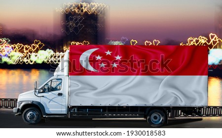 Singapore flag on the side of a white van against the backdrop of a blurred city and river. Logistics concept