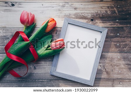 Photo frame and pink tulips on a wooden background. spring concept