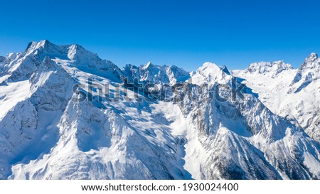 Caucasus Mountains, Panoramic view of the ski slope with the mountains Belalakaya, Sofrudzhu and Sulakhat on the horizon in winter day. Dombai ski resort, Western Caucasus, aerial photo