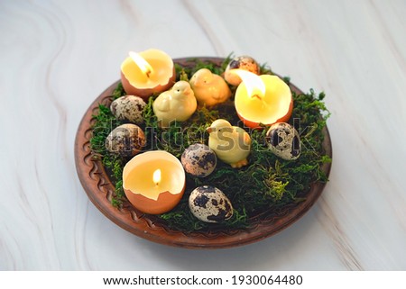 Easter composition - plate with moss, eggs and diy candles in eggs shells, decorative chickens. symbol Ostara sabbat and Easter holiday. festive spring season. wicca pagan tradition Royalty-Free Stock Photo #1930064480