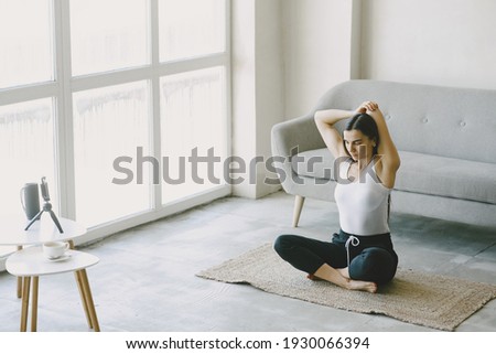 Girl looks at phone. Yogi kneading. Woman at home in a sports clothes.