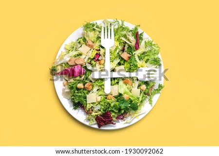 white forks on top of a lettuce salad, endive, arugula with cheese, chicken and croutons on a yellow background.Healthy food concept Royalty-Free Stock Photo #1930092062