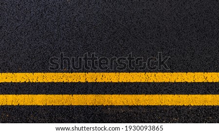 Yellow no parking lines on freshly laid tarmac road. Royalty-Free Stock Photo #1930093865