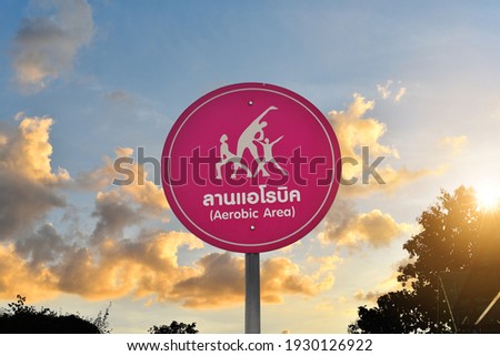 Aerobic Area,Thai-English text on Pink circle sign in front of cloudy sunset, with lens flares.