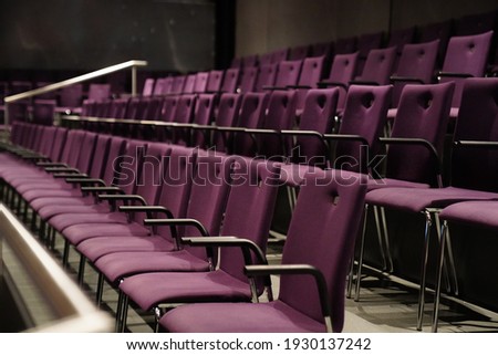 this picture shows purple chairs in a theater. no people are visible. the chairs have armrests and form a beautiful pattern.  Royalty-Free Stock Photo #1930137242