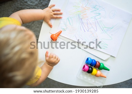 a child painting on a sheet on a table at home The child has col