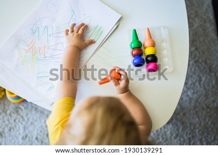 The hands of a child painting on a sheet on a table at home, wit
