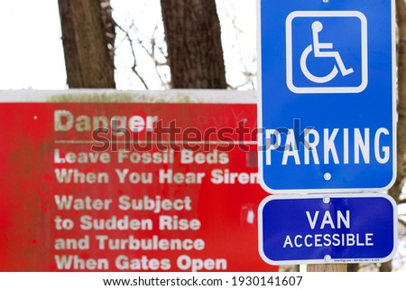 Handicap parking sign with a red Danger warning sign in the background