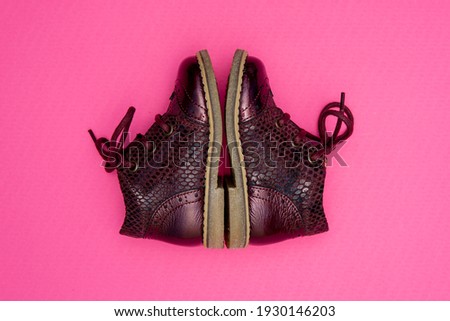 Baby girl leather shoes. Deep red. Pink background. Side view