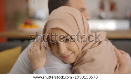 The happiness of a Muslim with headscarf woman wrapped on her husband's shoulder. Peaceful, happy family concept.