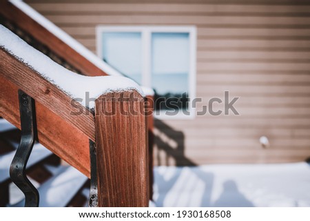 Steps leading to a wooden deck of a residential house with snow during the winter