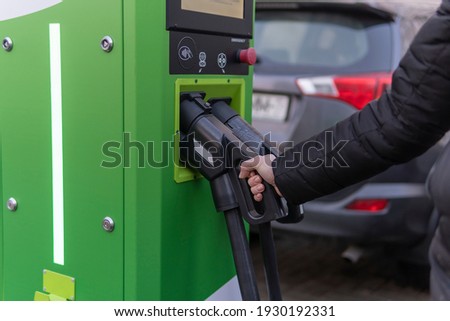 Girl to charge electric car. Hold in hand a cable to charge an electric car